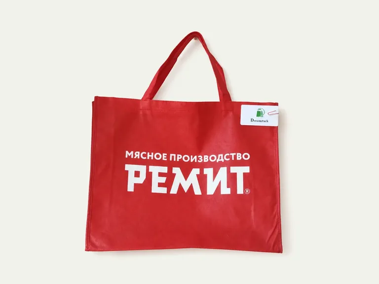 РЕМИТ — красная сумка из спанбонда с короткими ручками и крупной белой печатью логотипа.